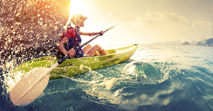 Young lady paddling in kayak with lots of splashes