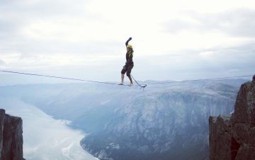 Man on tightrope over deep ravine taking a risk